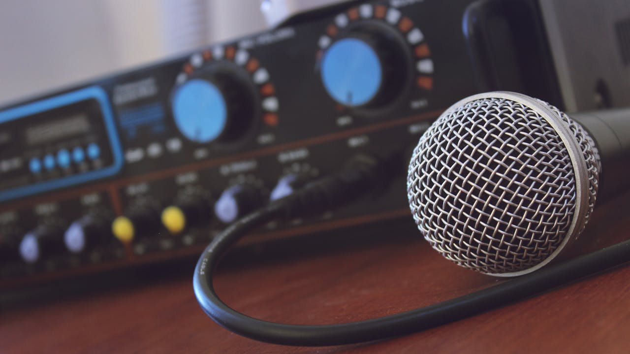 Focused shot of a microphone with audio mixer in background, ideal for media or music themes.